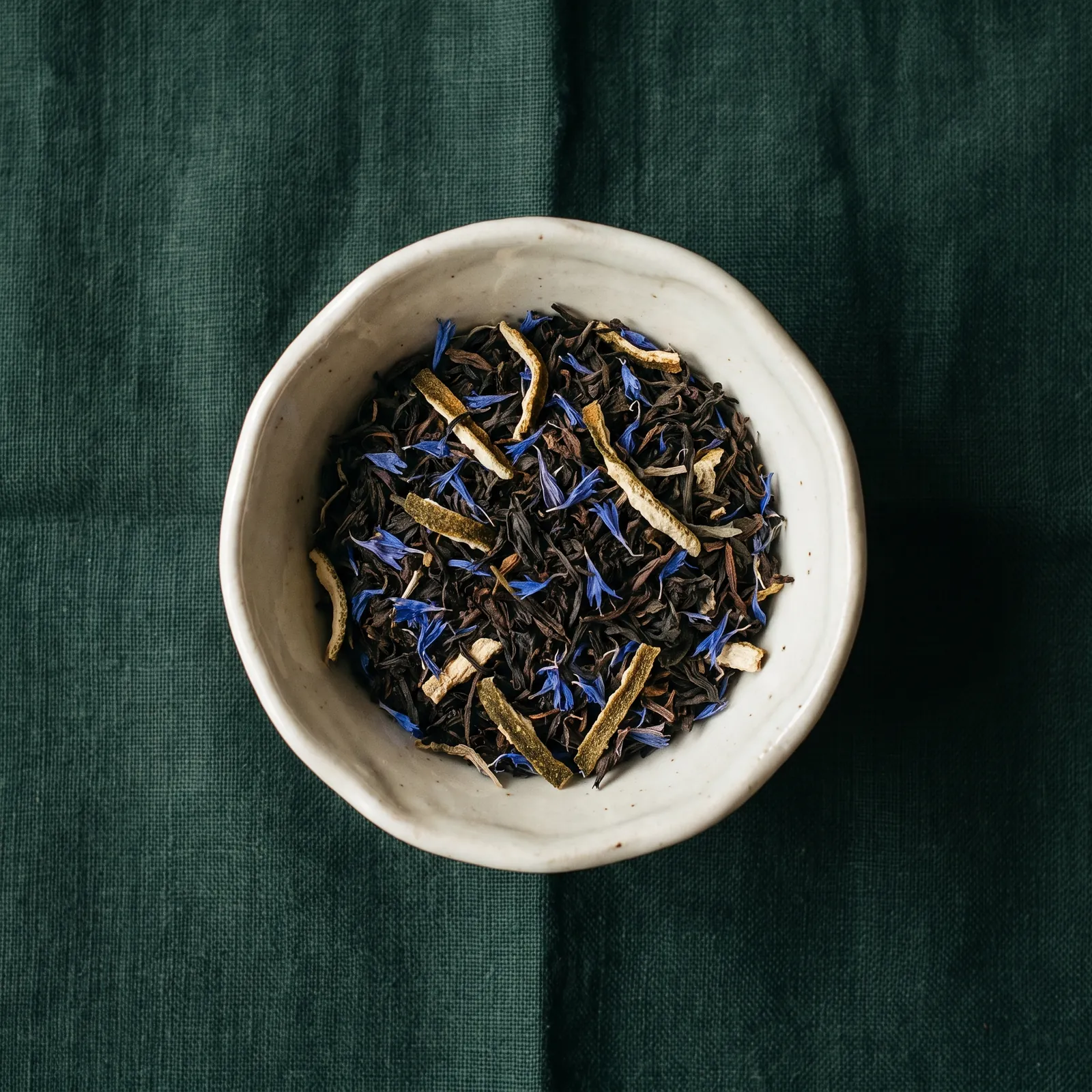 Schwarzer Tee mit blauen Kornblumen in einer Keramikschale