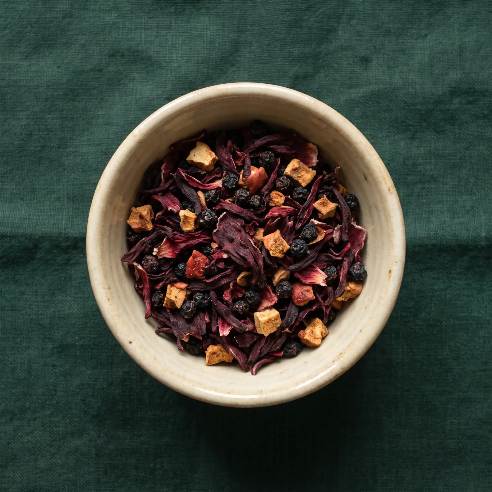 Rote Hibiskusblüten mit Holunderbeeren in einer Keramikschale