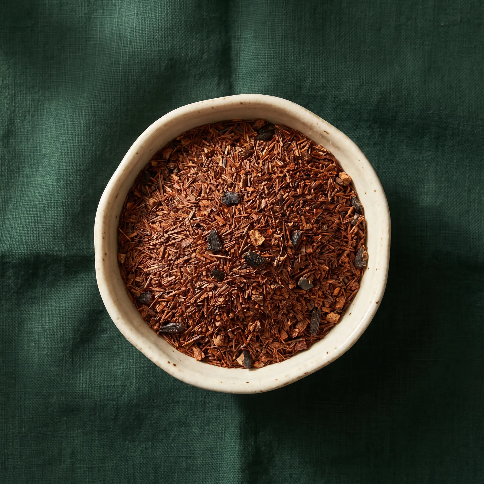Rotbraune Rooibos-Nadeln mit Vanillestücken in einer Keramikschale